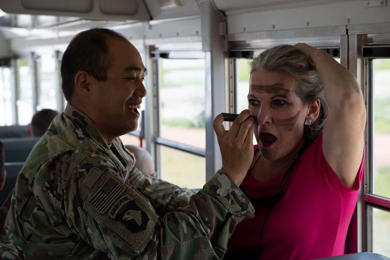 A soldier paints a civilian's face.