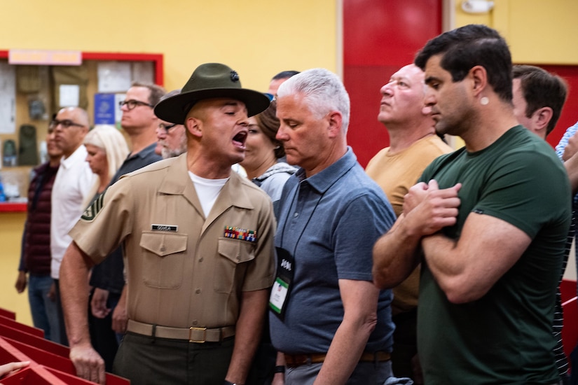 A Marine shouts and gets in the face of a civilian standing in a row of civilians.