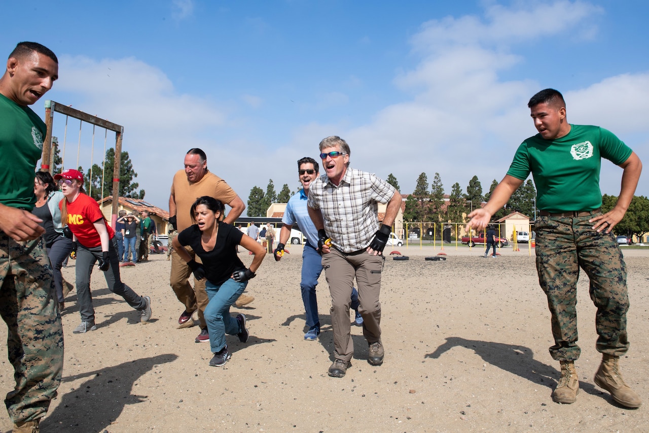 Marines give instruction as civilians conduct physical training outside.