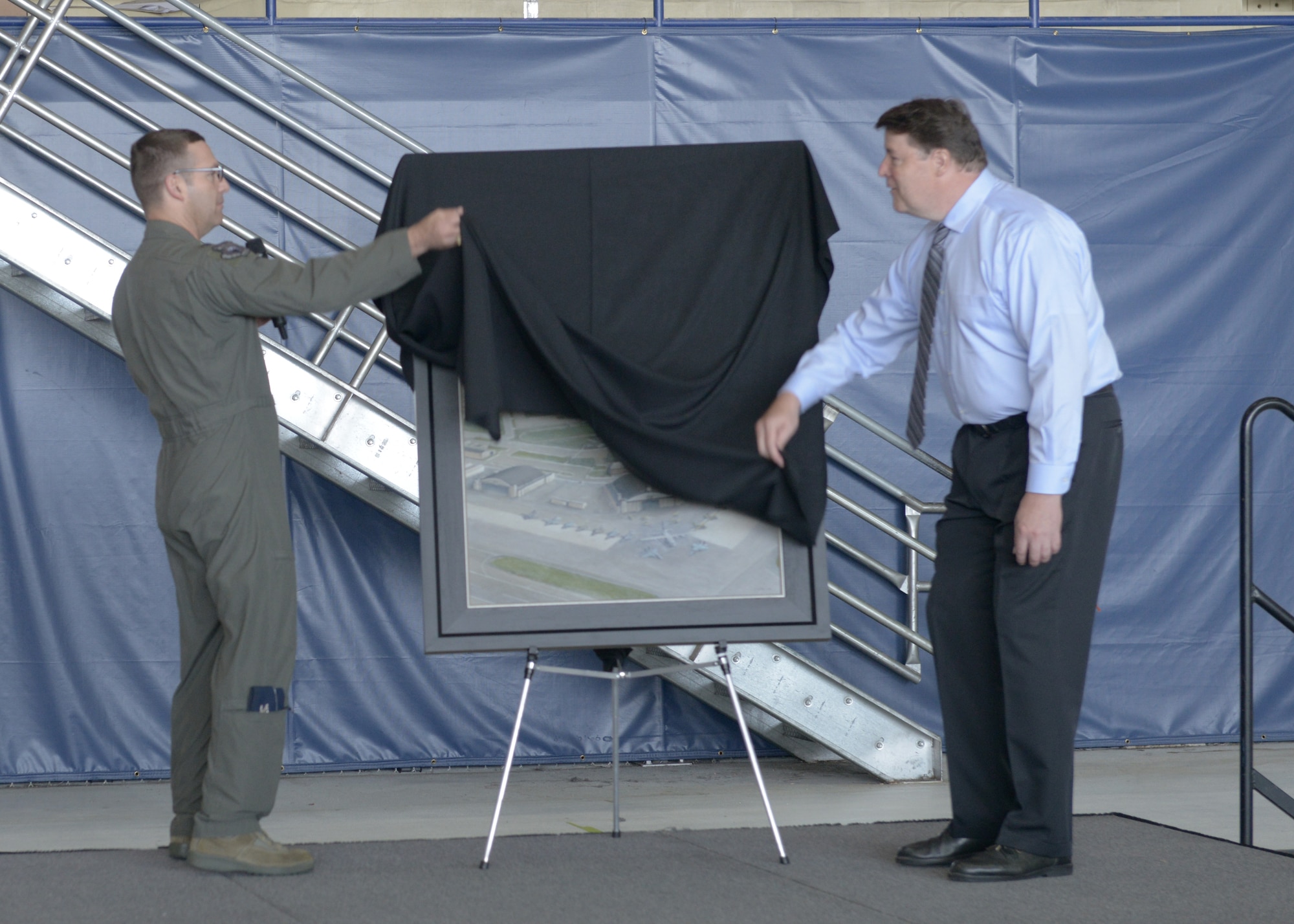 U.S. Air Force Col. Robert Davis, 3rd Wing commander, and John Hume, an artist, reveal a commemorative painting during the opening ceremony for the 3rd Wing’s 100th anniversary celebration on Joint Base Elmendorf-Richardson, Alaska, July 25, 2019.