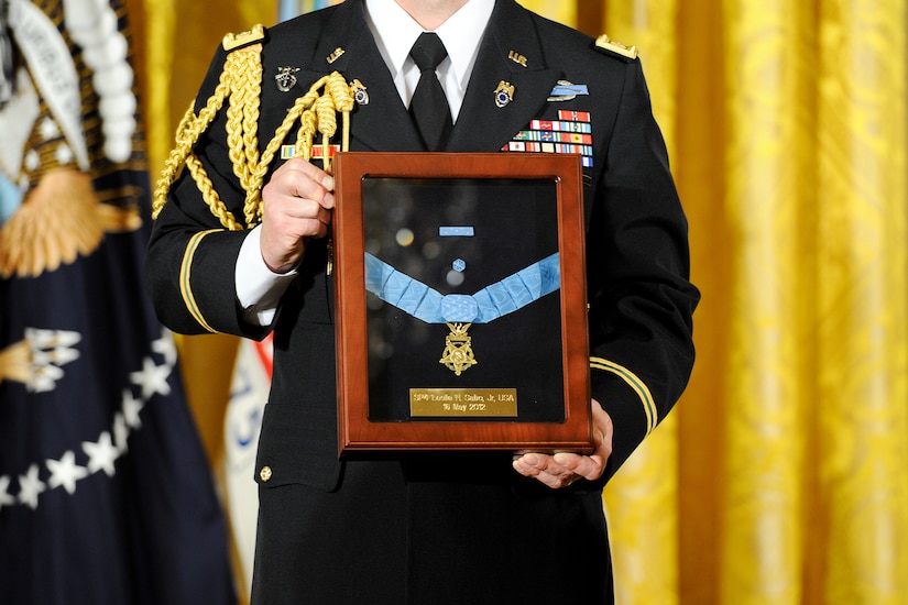 A soldier in dress uniform holds a case enshrining a Medal of Honor.