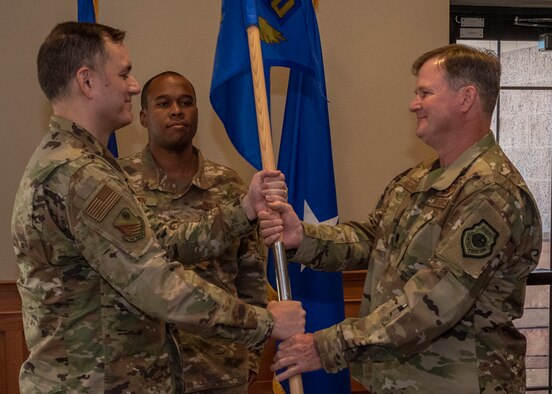 An Airman passes a guidon to another Airman.