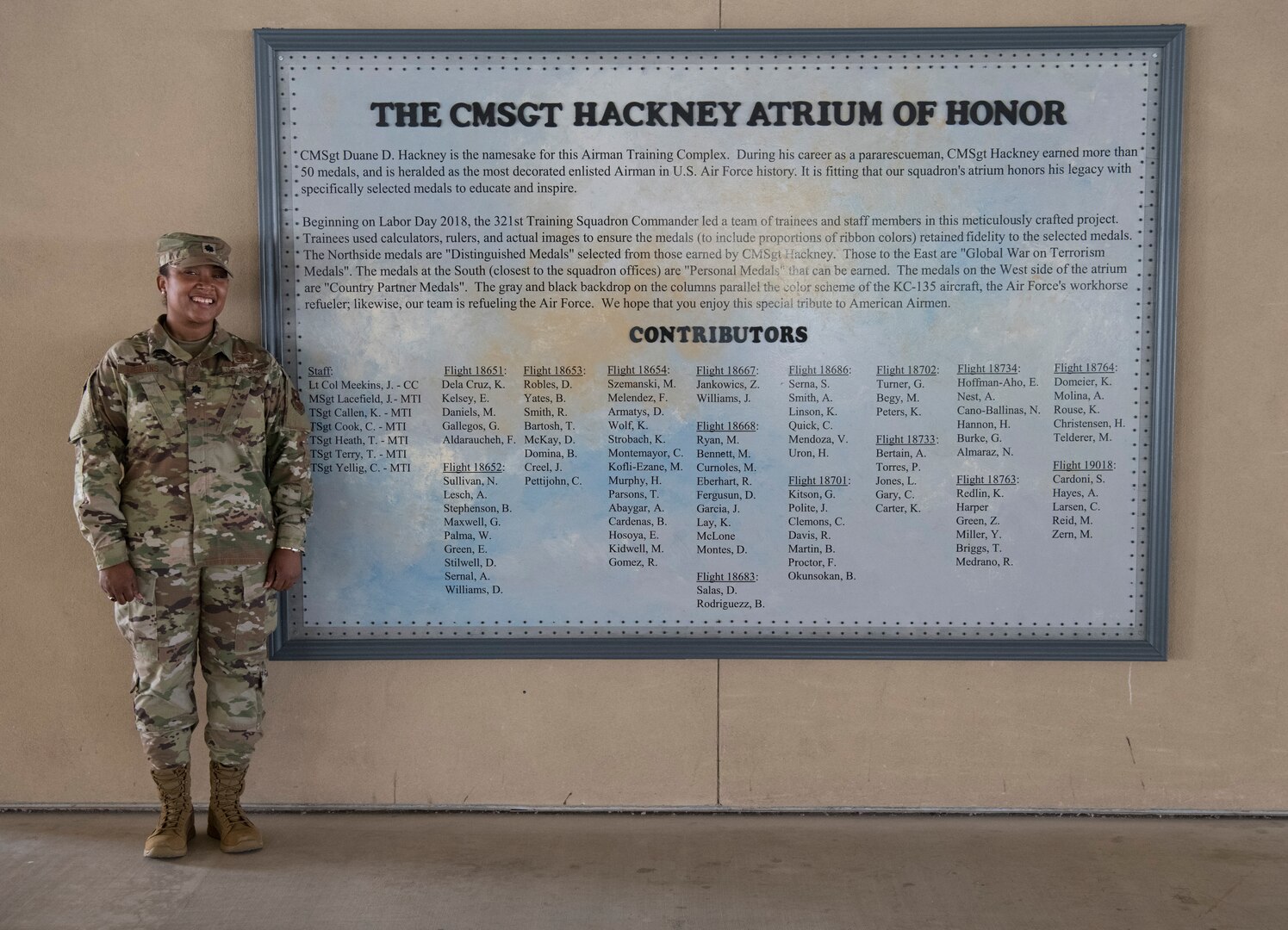 Lt. Col. Jeurney Meekins, 321 st Training Squadron former commander, poses in front of plaque for a series of murals depicting military medals July 17, 2019, at Joint Base San Antonio- Lackland, Texas.