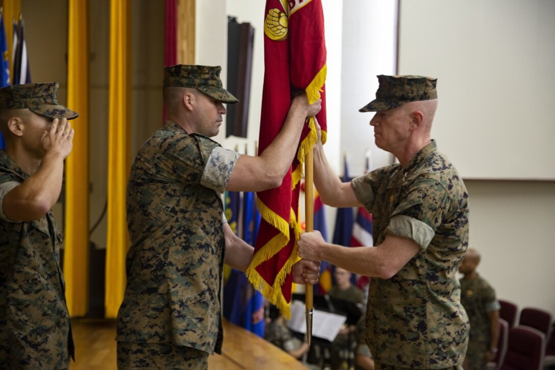 U.S. Marine Corps Sgt. Maj. Michael J. West presents the Marine Corps to U.S. Marine Corp Maj. Gen. Paul J. Rock Jr. during the 3D Marine Expeditionary Brigade assumption of command at the Camp Courtney Theater, July 26, 2019. Rock assumes command as the deputy commanding general of the III Marine Expeditionary Force and commanding general of the 3rd Marine Expeditionary Brigade. The assumption of command ceremony represents the relinquishing of power from one commanding general to another. (U.S. Marine Corps photo by Sgt. George Melendez)