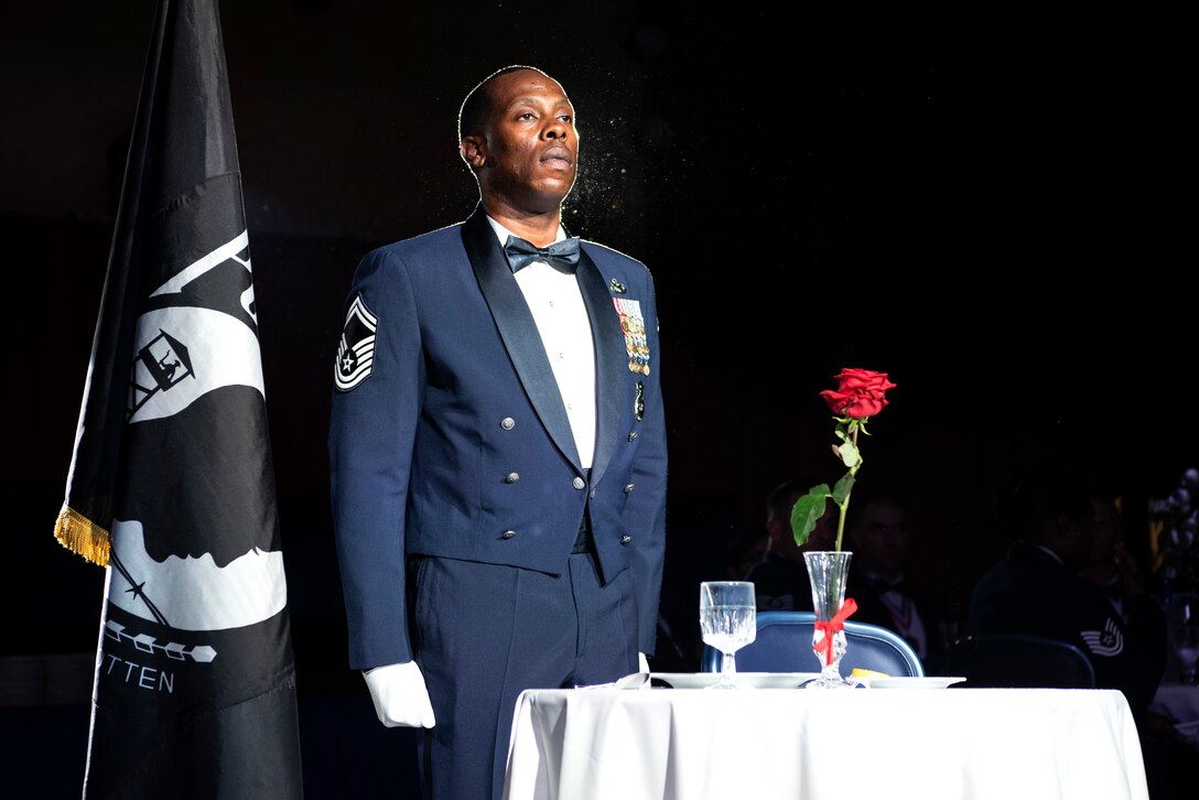 U.S. Air Force Senior Master Sgt. Jerrme Stanton, 702nd Munitions Support Squadron security forces manager, conducts a missing-in-action and prisoner-of-war presentation during a senior NCO induction ceremony at Spangdahlem Air Base, Germany, July 26, 2019. The seat was empty in remembrance of fallen and missing service members. (U.S. Air Force photo by Airman 1st Class Valerie Seelye)