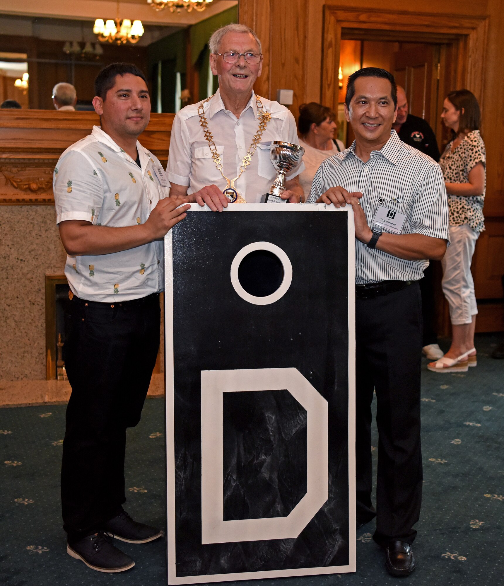 U.S. Air Force  Tech. Sgt. Sergio Villela, 100th Civil Engineer Squadron firefighter, left, Councillor Harry Humphrey, Norfolk County Council chairman, and Col. Troy Pananon, 100th Air Refueling Wing commander, pose for a photo after winning the New Mayors’ Barbecue cornhole tournament at RAF Mildenhall, England, July 27, 2019. The event informed local community leaders about the base and gave them a chance to get to know the base leadership on a personal level and strengthen partnership. (U.S. Air Force photo by Airman 1st Class Brandon Esau)
