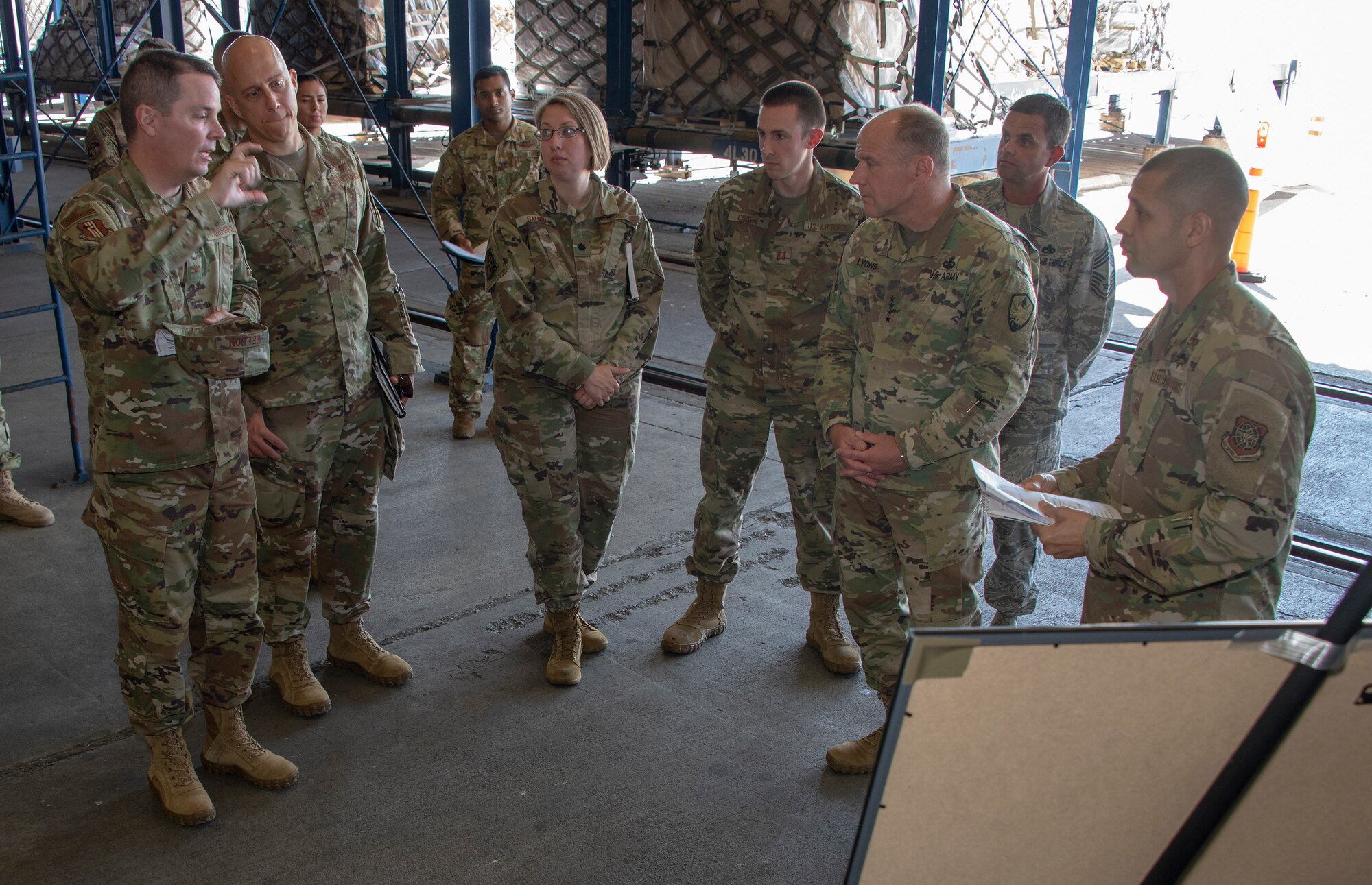 U.S. Army Gen. Steve Lyons, center left, U.S. Transportation Command commander, Scott Air Force Base, Illinois, listens to Col. Jeffrey Nelson, far left, 60th Air Mobility Wing commander, during a visit to the 60th Aerial Port Squadron warehouse, July 24, 2019 at Travis Air Force Base, California. Lyons had the opportunity to interact with Travis Airmen and tour several units while on the base visit. (U.S. Air Force photo by Heide Couch)