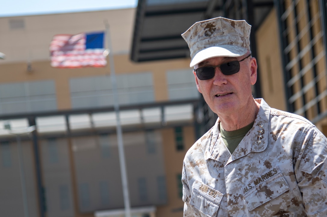 A man walks with an American flag flying in the background.