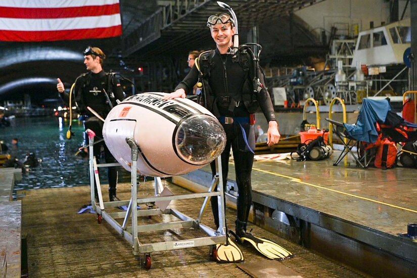 A student poses next to a human-powered submarine.