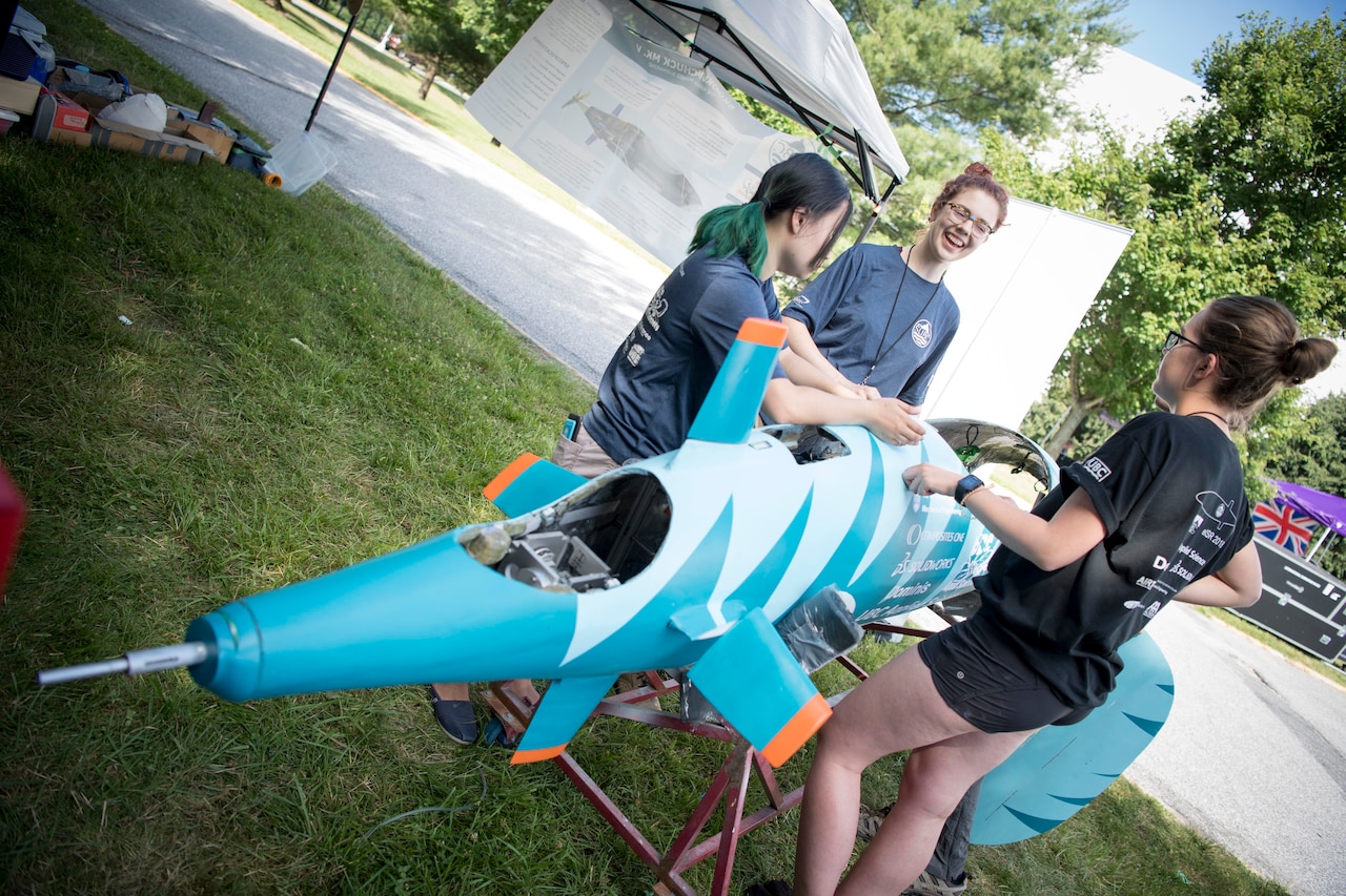 Students perform maintenance on their human-powered submarine.