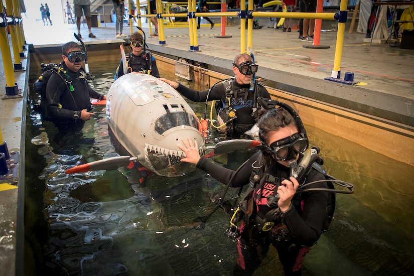Students lower their human-powered submarine into the water.