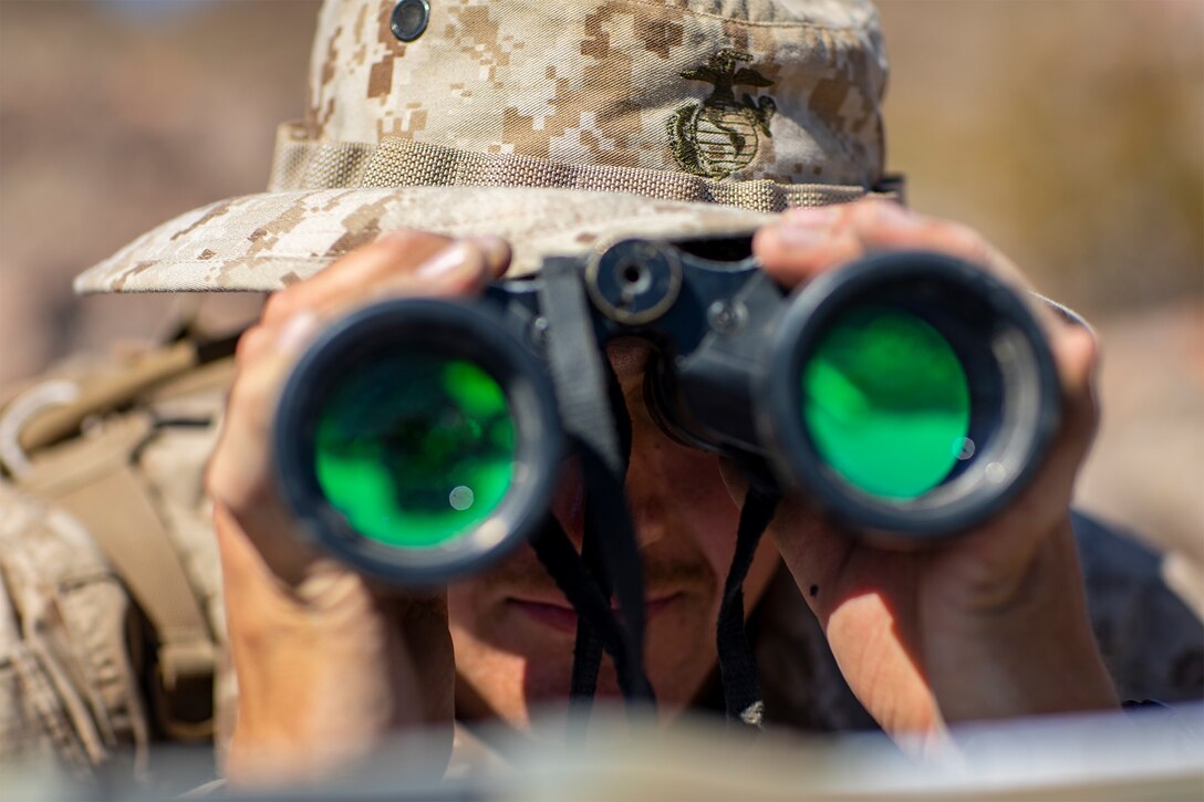 A Marine looks through binoculars.