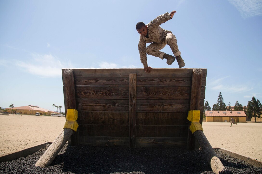 A Marine jumps over a wall barrier.