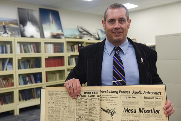 Scott Bailey, 30th Space Wing historian, showcases an archived July 1969 issue of the "Mesa Missilier", a publication which served as base newspaper during the Apollo 11 lunar mission. Utilizing publications like this in the 30th SW history archive, Bailey is able to take the Wing's past legacy of accomplishment and tie it to current and future operations and the mission of the Wing. (U.S. Air Force photo by Michael Peterson)