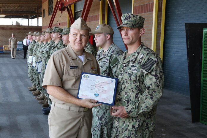 Rear Adm. Tom Anderson presents a Navy Afloat Maintenance Training Strategy certificate to Machinist Mate Second Class Paul Lewis at Puget Sound Naval Shipyard & Intermediate Maintenance Facility Everett Detachment during an all-hands presentation in Everett, Washington. Anderson is Commander, Navy Regional Maintenance Center and Naval Sea Systems Deputy Commander, Ship Maintenance and Modernization (SEA 21) and visited Northwest Regional Maintenance Center (NWRMC) on Jul 22.