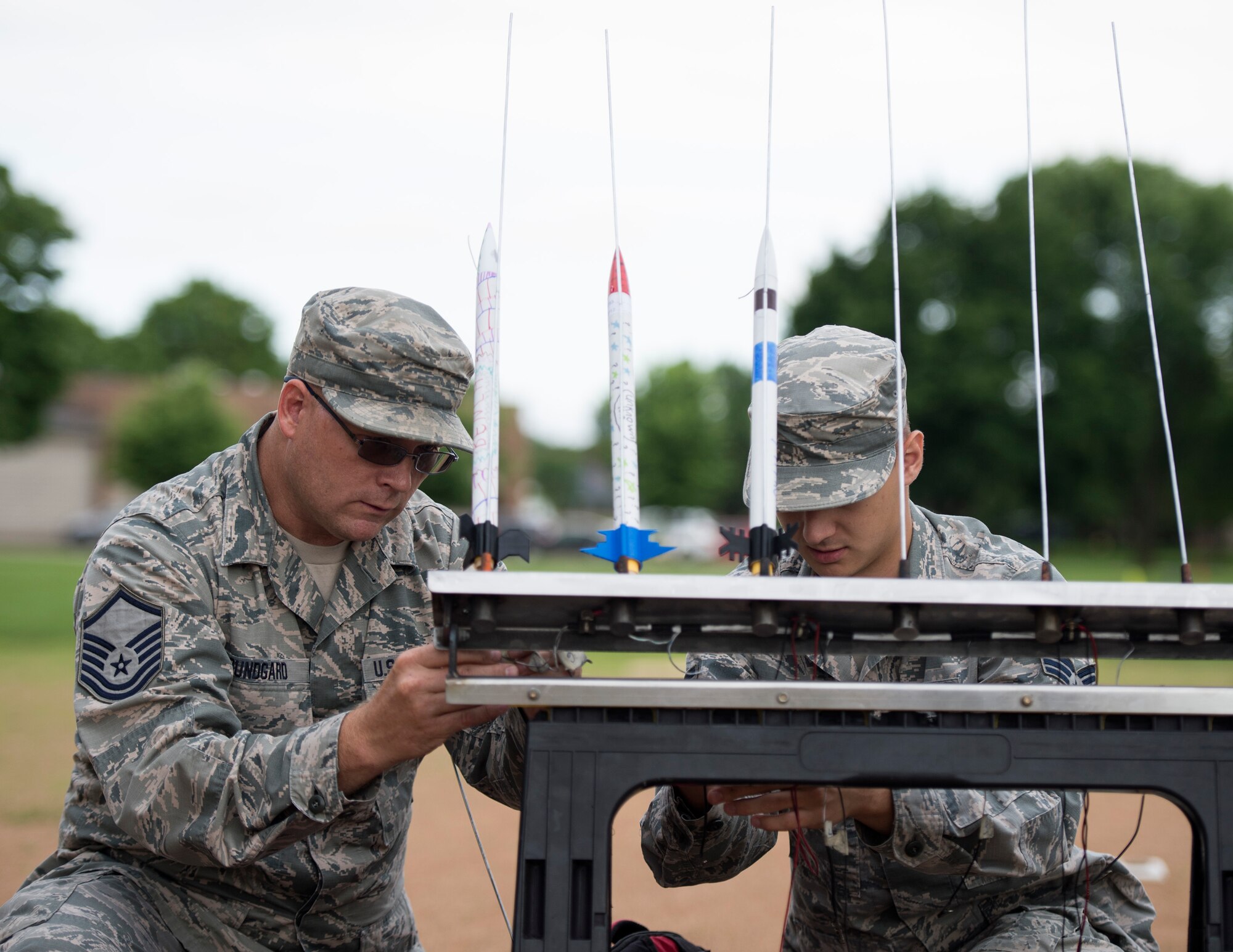 U.S. Air Force Master Sgt. Jeremy Bundgard, 133rd Logistics Readiness Squadron, left, and Senior Airman Geoffrey Slaughter, 133rd Aircraft Maintenance Squadron, attach wires to the rockets in St. Paul, Minn., July 18, 2019.