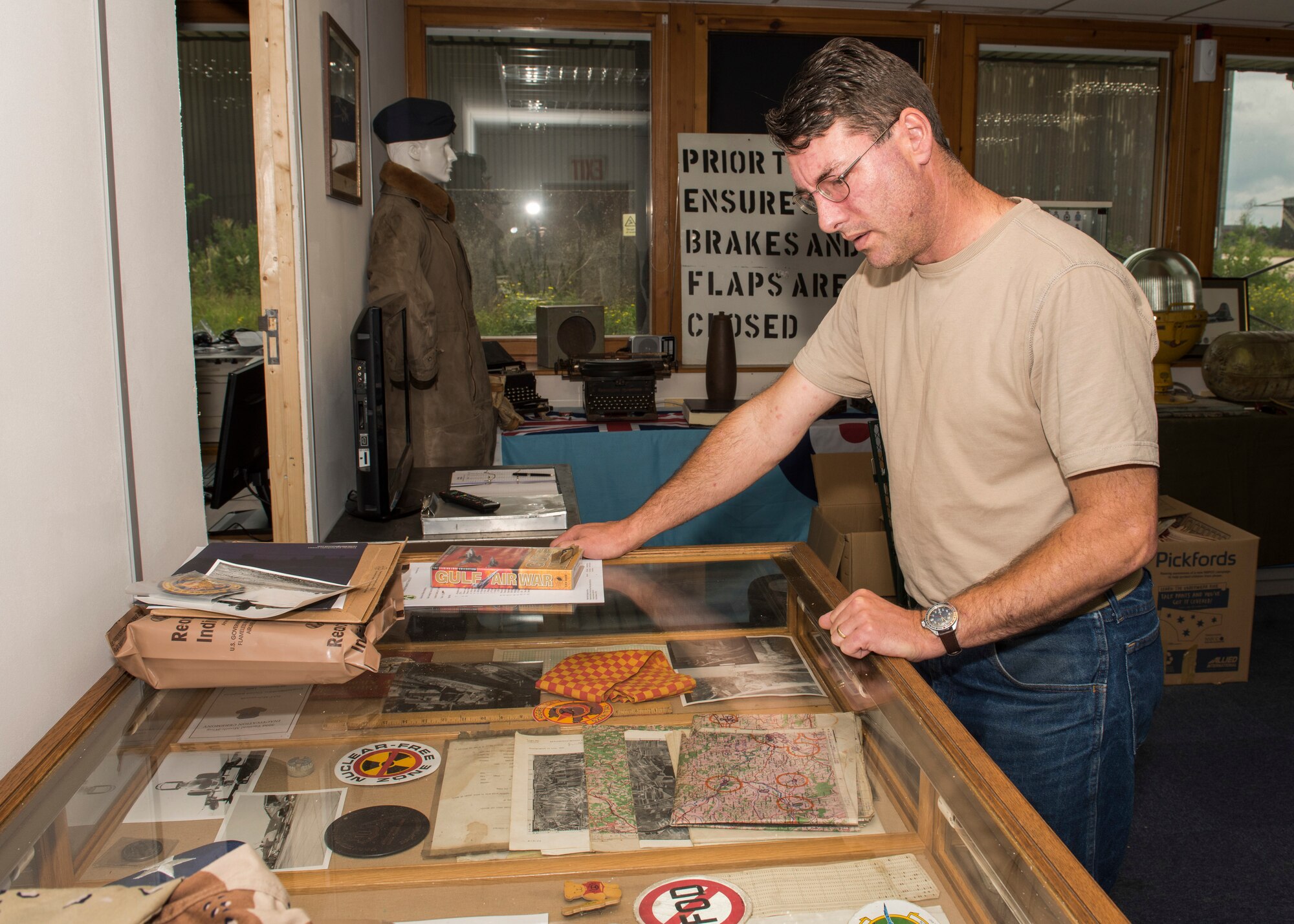 Paul George Bellamy, Airfield Research Group director of archives and collections, stands by a display case of RAF Alconbury memorabilia at the Alconbury Airfield Heritage Collection, England, July 14, 2019. The display case showcased historical items ranging from the World War II era to the closing of the flight line. (U.S. Air Force photo by Airman 1st Class Jennifer Zima)