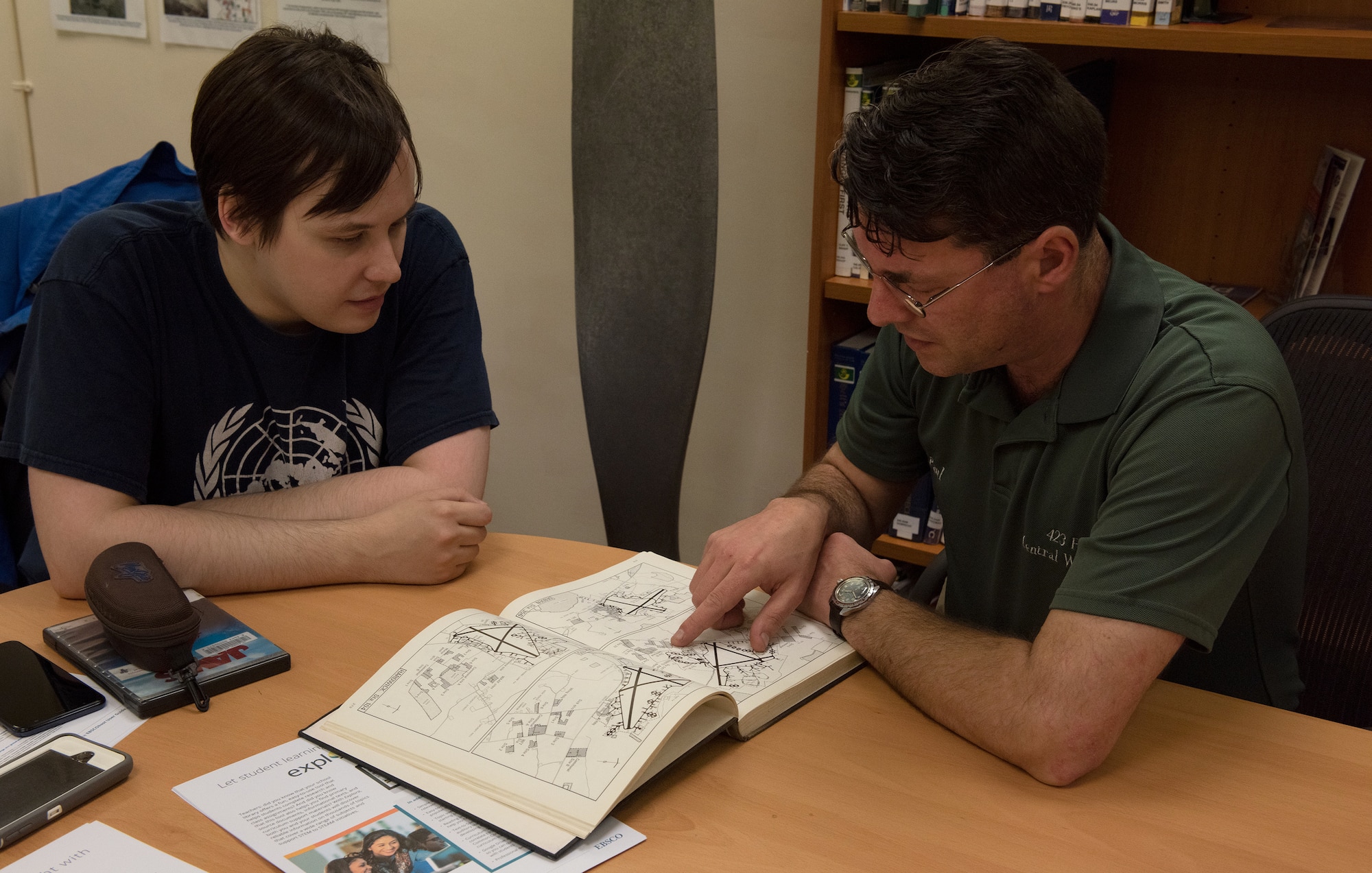 Paul George Bellamy, Airfield Research Group director of archives and collections, shows Christopher Klimovitz maps inside “The Mighty Eighth War Manual” by Roger Freeman at the Alconbury Heritage Room, at the RAF Alconbury library, England, May 1, 2019. RAF Debden was a fighter station actively used from 1937-1975 by the Royal Air Force and the U.S. Army Air Force. (U.S. Air Force photo by Airman 1st Class Jennifer Zima)