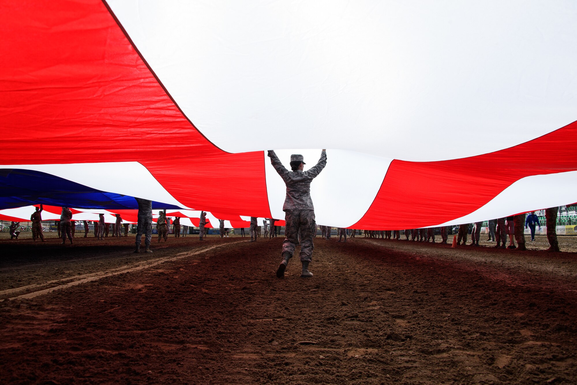 Hill Air Force Base Airmen alongside other military members and first responders serving in Utah unfurl an American flag during Patriot Night at the Ogden Pioneer Days Rodeo in Ogden, Utah, July 22, 2019.