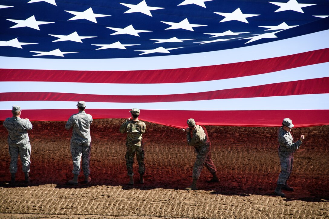 Hill Air Force Base Airmen alongside other military members and first responders serving in Utah unfurl an American flag during Patriot Night at the Ogden Pioneer Days Rodeo in Ogden, Utah, July 22, 2019.