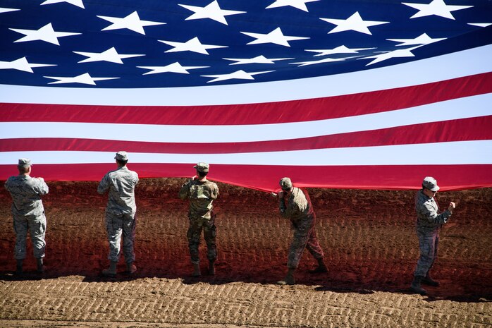 Hill Air Force Base Airmen alongside other military members and first responders serving in Utah unfurl an American flag during Patriot Night at the Ogden Pioneer Days Rodeo in Ogden, Utah, July 22, 2019.