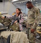 Maj. Gen. Patrick D. Sargent (right), commanding general of the U.S. Army Medical Department Center and School Health Readiness Center of Excellence, visits with Roberta, a machine operator, while she sews the sleeve of an Army Combat Shirt. Roberta has very little vision and is in the Lighthouse Choir.