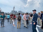 Lt. j.g. Sebastian Welch (right) gives Naval Surface Warfare Center, Carderock Division employees and interns an overview of USS Mahan’s (DDG 72) helo deck before embarking on a tour of the Arleigh Burke-class destroyer during Carderock’s “Meet-the-Fleet” trip to Naval Station Norfolk on July 16, 2019. (U.S. Navy photo by Lydia Weyrich/Released)