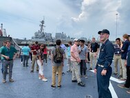 Lt. j.g. Sebastian Welch (right) gives Naval Surface Warfare Center, Carderock Division employees and interns an overview of USS Mahan’s (DDG 72) helo deck before embarking on a tour of the Arleigh Burke-class destroyer during Carderock’s “Meet-the-Fleet” trip to Naval Station Norfolk on July 16, 2019. (U.S. Navy photo by Lydia Weyrich/Released)