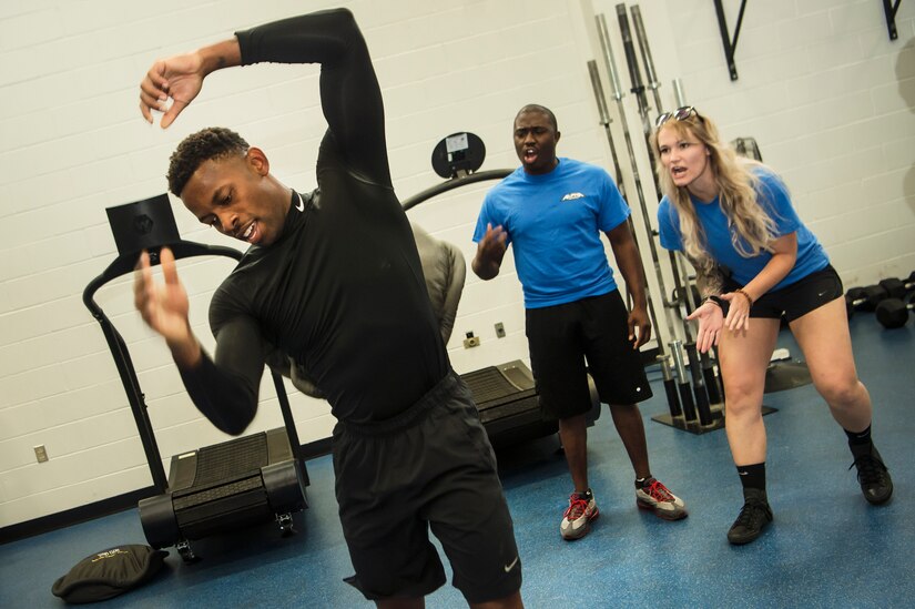 U.S. Air Force Staff Sgt. Robert Carter, left, 628th Force Support Squadron sports manager, throws a 100-pound sandbag over his shoulder as Staff Sgt. Chris Morrison, center, 628th FSS shift leader, and Senior Airman Sierra Romero, right, 628th FSS fitness journeyman, cheer him on during the Alpha Warrior Super Regional event July 27, 2019, at Joint Base Charleston, S.C. Twelve Airmen competed, tackling a variety of functional fitness obstacles, while utilizing the Joint Base Charleston Fitness Center’s Alpha Warrior battle rig. The competition focuses on a competitor’s overall readiness and is designed to promote more fit and resilient service members.