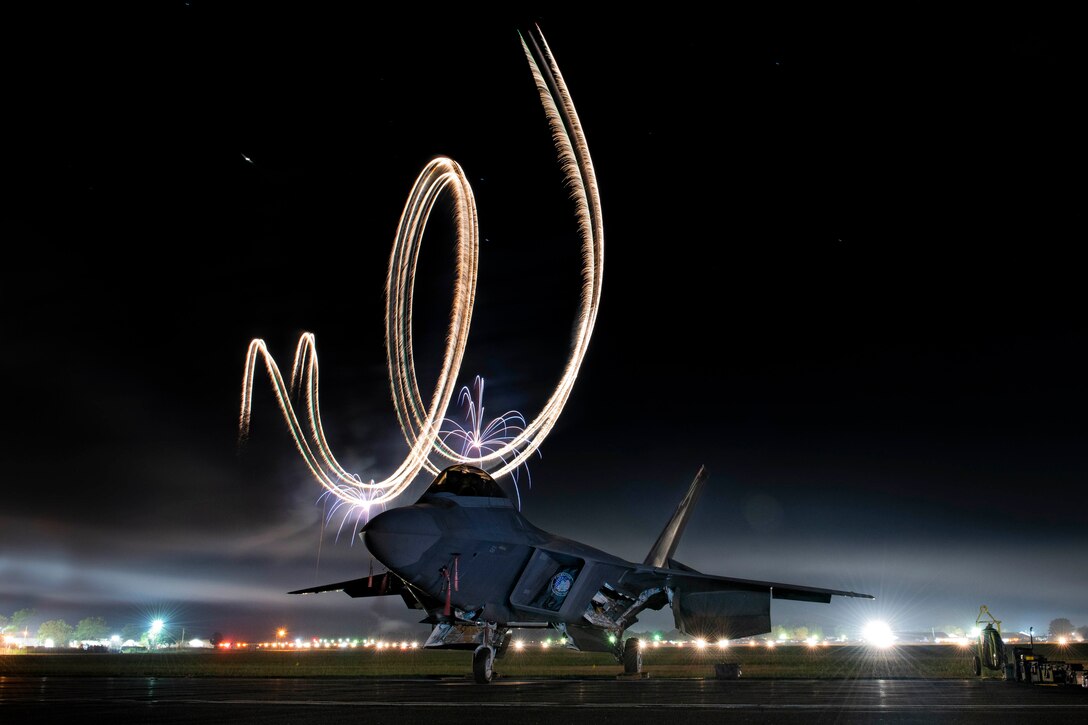 A plane sits parked with  lights in the sky.