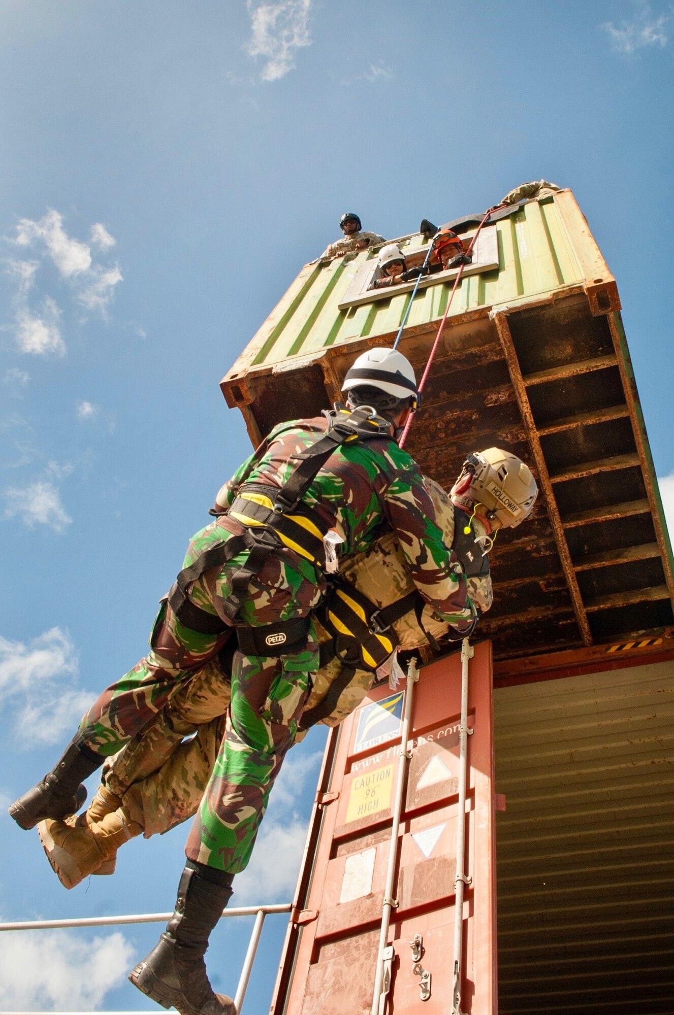 An Indonesian soldier assists a simulated wounded Hawaii Army National Guardsman as he repels from a second story building during a Combined - Multinational Task Force [CTF 501] search and extraction training scenario on July 18, 2019 at Kalaeloa Urban Search and Rescue Training area, Hawaii. Service members from the Philippines, Indonesia, Bangladesh, Vietnam, Oregon Air National Guard traveled to Hawaii as part of a State Partnership Program training event.
