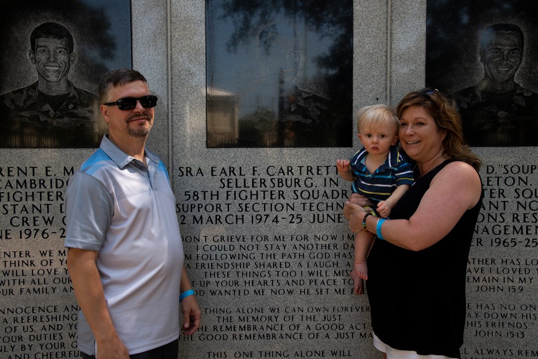 Jerry and Sally Adams pose in front of Senior Airman Earl Cartrette Jr.’s memorial with their child at Eglin Air Force Base, Florida, on July 29, 2019. Sally was adopted when she was two weeks old and spent her life searching for her biological family. Upon finding out her brother had died in the 1996 Khobar Towers attack she and her family made the visit to Eglin to see the memorial. (U.S. Air Force photo by Senior Airman Cassidy Woody)