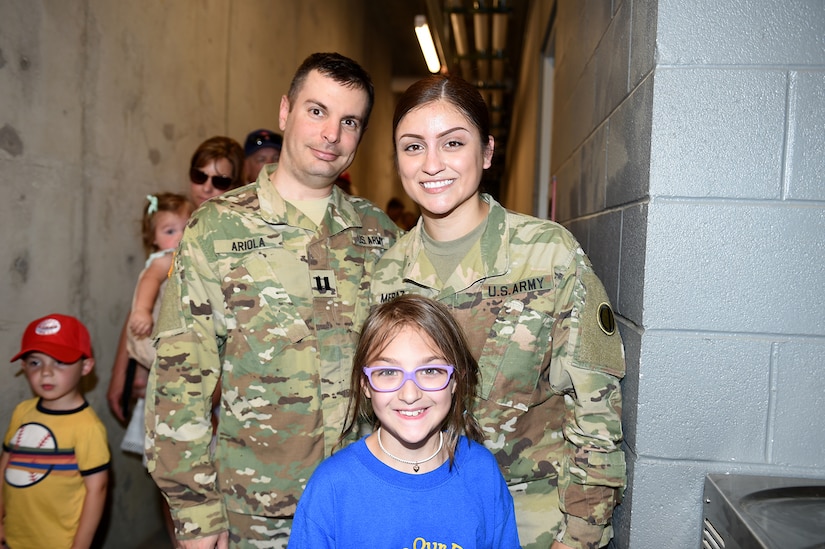 U.S. Army Reserve Capt. Michael Ariola, left, and Sgt. Maribel Meraz, assigned to the 85th U.S. Army Reserve Support Command headquarters, pause for a photo with Mae Gossage, 8, who wanted to meet Meraz and stated that she did not know that women can join the Army, during the American Association of Independent Professional Baseball’s Chicago Dogs baseball home game, July 28, 2019, at Impact Field in Rosemont, Illinois against the Cleburne Railroaders.