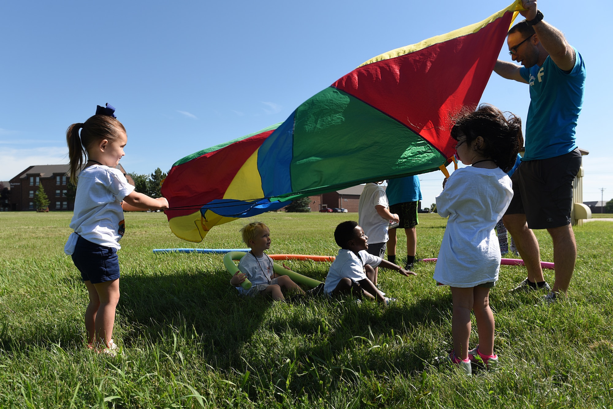 Children play with a parachute at Vacation Bible School at the Chapel Community Center at Ellsworth Air Force Base, S.D., July 21, 2019. Approximately 70 children, ages 6 through 12, participated in the weeklong event, which had songs, bible lessons, cinema time, and outdoor activities. (U.S. Air Force photo by Airman Quentin K. Marx)