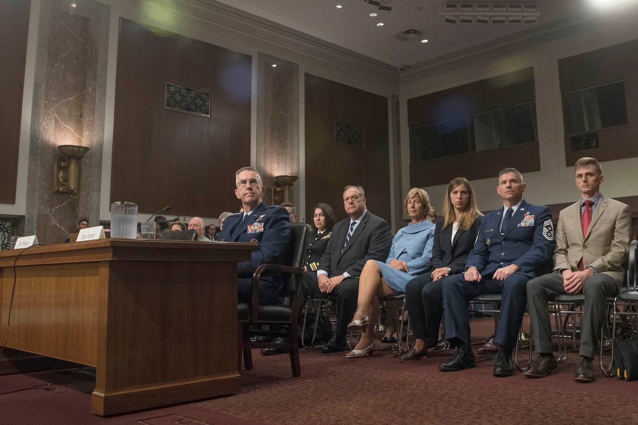 Air Force Gen. John E. Hyten sits at a table with a row of audience members behind him.