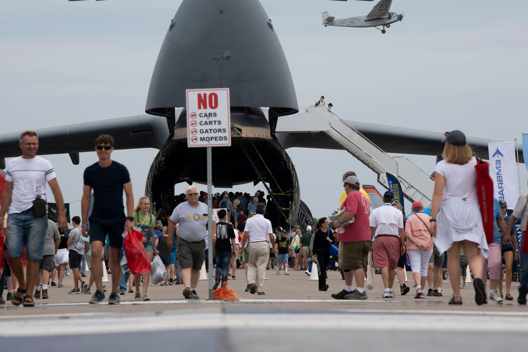 EAA AirVenture attendees walk in front of a C-5M Super Galaxy July 26, 2019, at Whitman Regional Airport in Oshkosh, Wisconsin. The C-5 crew went to EAA AirVenture 2019 where more than 500,000 aviation enthusiasts from 80 countries gathered at the air show to celebrate the past, present and future in the world of aviation. (U.S. Air Force photo by Senior Airman Jonathon Carnell)