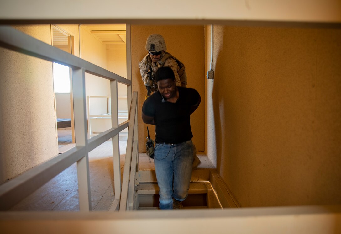 U.S. Marine Corps Sgt. Greg Whittaker, a rifleman with 1st Battalion, 25th Marine Regiment, 4th Marine Division, escorts a detainee down a flight of stairs at Marine Corps Air Ground Combat Center Twentynine Palms, Calif., July 30, 2019, during Integrated Training Exercise 5-19. ITX 5-19 is an essential component of the Marine Forces Reserve training and readiness cycle. It serves as the principle exercise for assessing a unit’s capabilities. (U.S. Marine Corps photo by Sgt. Andy O. Martinez)