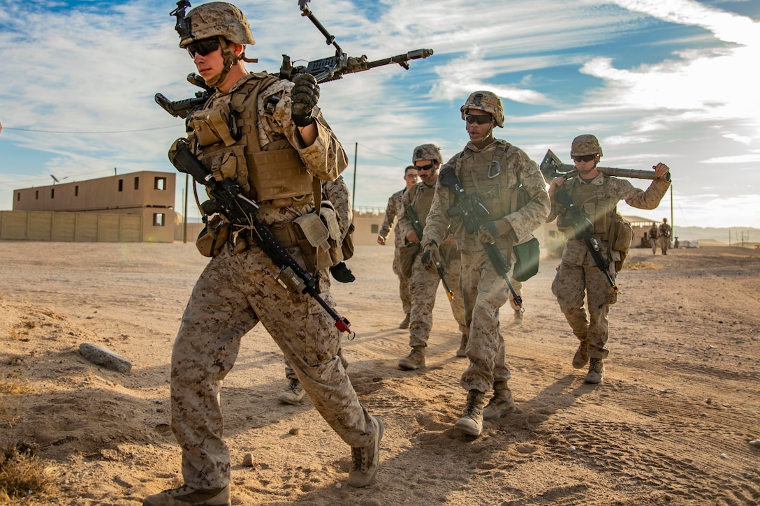 A group of Marines hike with their weapons.