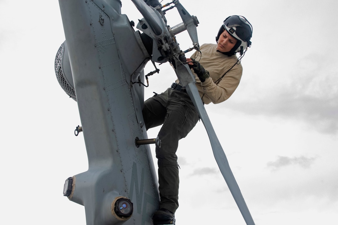 A sailor inspects an aircraft part.