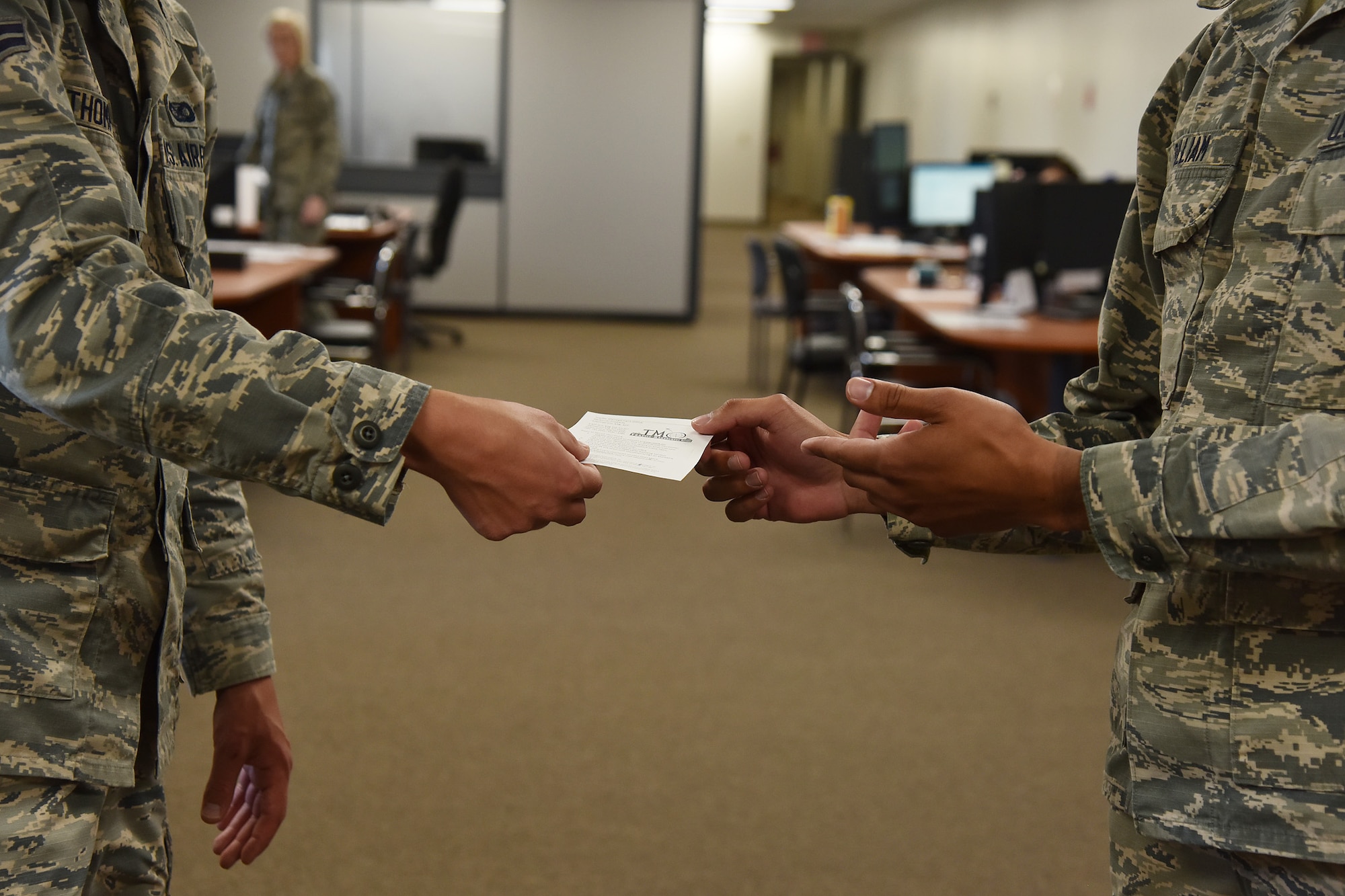 Airman 1st Class Lejavin Pulliam, 341st Logistics Readiness Squadron personal property counselor, hands a customer paper to assist with creating an account on move.mil July 29, 2019, at Malmstrom Air Force Base, Mont. traffic management office.