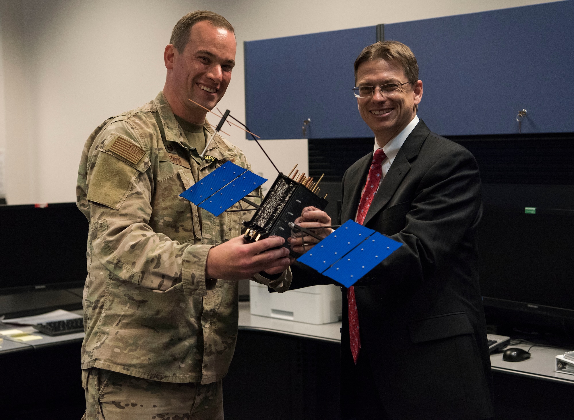 Johnathon Caldwell, Lockheed Martin Space vice president of navigation systems, right, presents Lt. Col. Stephen Toth, 2nd Space Operations Squadron commander, with a GPS III model satellite as a token of appreciation for the 2nd SOPS critical mission in space at Schriever Air Force Base, Colorado, July 29, 2019. The 2nd SOPS operates the largest Department of Defense spacecraft constellation using the Master Control Station and a worldwide network of monitor stations and ground antennas. (U.S. Air Force photo by Airman 1st Class Jonathan Whitely)