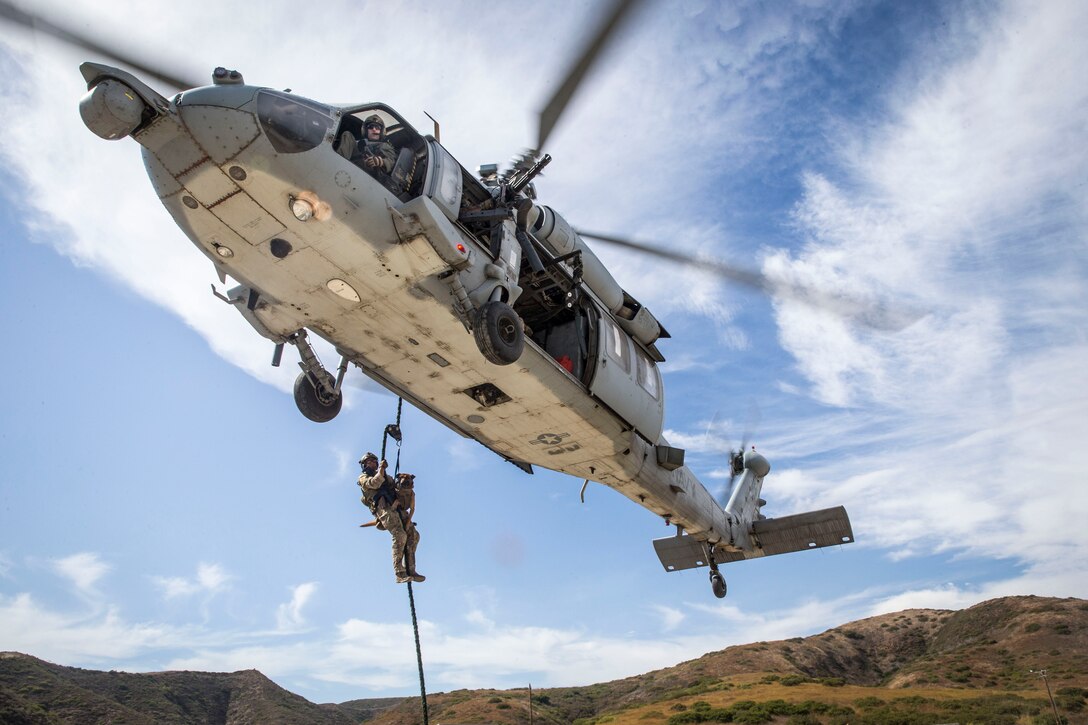 A U.S. Army Ranger military working dog handler fast-ropes from a U.S. Navy MH-60 Seahawk helicopter during a training evolution as part of a multipurpose canine subject matter expert exchange hosted by 1st Marine Raider Battalion, U.S. Marine Corps Forces Special Operations Command, on Marine Corps Base Camp Pendleton, California, July 24, 2019. The purpose of the MARSOC-hosted SMEE was to bring canine handlers together from different agencies and branches to conduct maritime and land-based training while exchanging tactics, techniques and procedures. (U.S Marine Corps photo by Lance Cpl. Drake Nickels)