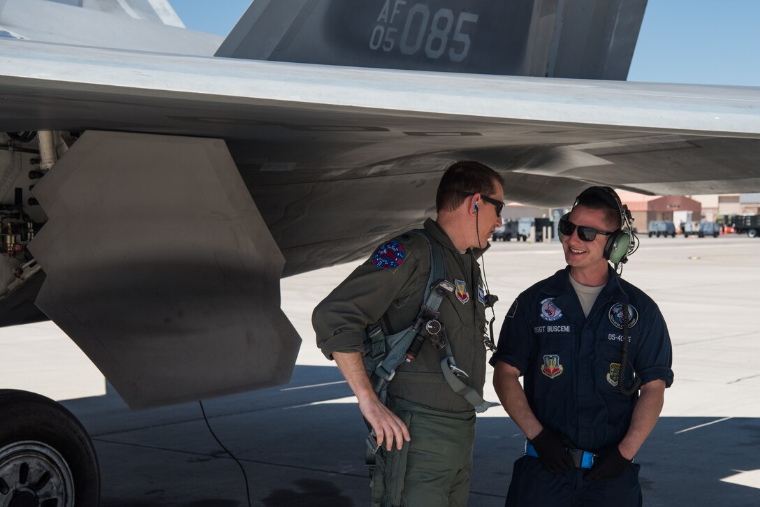 U.S. Air Force Staff Sgt. Lenny Buscemi, 94th Aircraft Maintenance Unit dedicated crew chief, speaks with Lt. Col. David Delmage, 94th Fighter Squadron F-22 Raptor pilot, before takeoff at Nellis Air Force Base, Nevada, July 18, 2019.