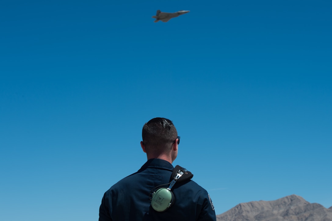 U.S. Air Force Staff Sgt. Lenny Buscemi, 94th Aircraft Maintenance Unit dedicated crew chief, watches an F-22 Raptor after takeoff at Nellis Air Force Base, Nevada, July 18, 2019.