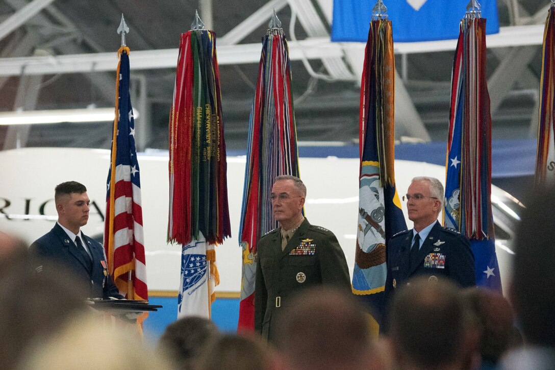 Three people stand in front of a crowd.