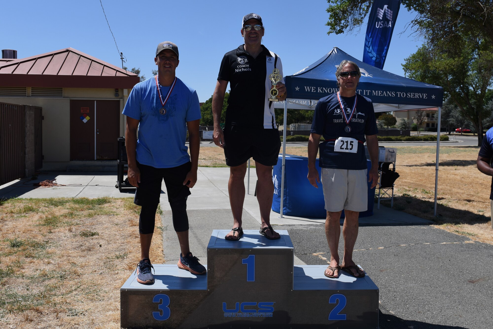 From left to right, U.S. Air Force Tech. Sgt. Peter Realbird, 945th Aircraft Maintenance Squadron, William Nichols, 60th Operations Support Squadron, and David Lausch, stand on the first, second and third place podiums July 27, 2019, at Travis Air Force Base, California. During the triathlon, which is in its 26th year, 31 athletes competed against one another. Participants had to swim 400 meters, bike 12 miles and run 3.1 miles. (U.S. Air Force Photo by Airman 1st Class Cameron Otte)