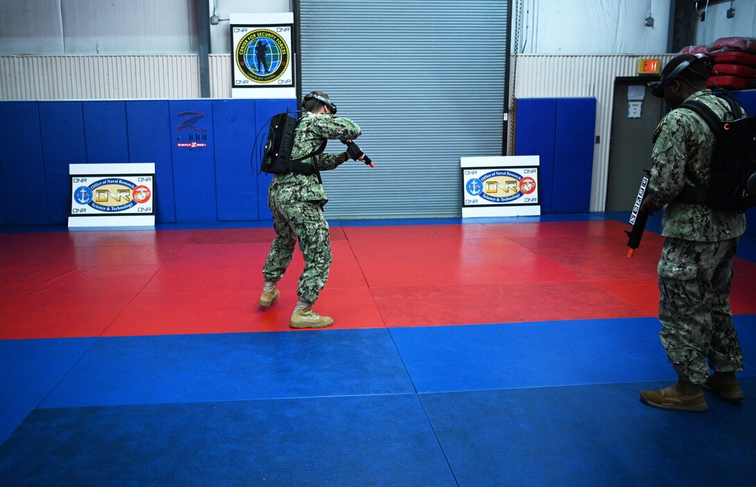 IMAGE: 190613-N-PO203-0186 CHESAPEAKE, Virginia (Jun. 13, 2019) Sailors assigned to the Center for Security Forces detachment in Chesapeake, Va., demonstrate the Office of Naval Research Global (ONRG) TechSolutions-sponsored Tactically Reconfigurable Artificial Combat Enhanced Reality (TRACER) system. TechSolutions partnered with Naval Surface Warfare Center Dahlgren Division to develop the TRACER package, which consists of a virtual-reality headset, a backpack, a state-of-the-art simulated weapon designed to deliver realistic recoil, and a software package that creates multiple and adaptable simulation scenarios for security personnel to experience. ONRG TechSolutions allows Sailors and Marines to submit technology requests directly to the development community for rapid response prototyping. (U.S. Navy photo by John F. Williams)