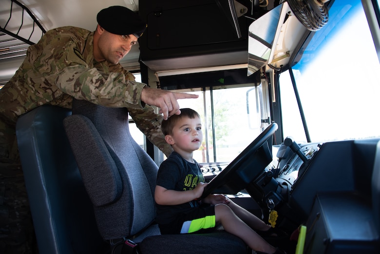 Cason, 4, sits in the driver’s seat of a school bus as Tech. Sgt. Donny Turner, Security National Reconnaissance Office non-commissioned officer in charge, guides him during the back-to-school event at Schriever Air Force Base, Colorado, July 30, 2019. The event provided educational resources and information from a variety of organizations and the Ellicott Schools in preparation for the upcoming school year. (U.S. Air Force photo by 2nd Lt. Idalí Beltré Acevedo)