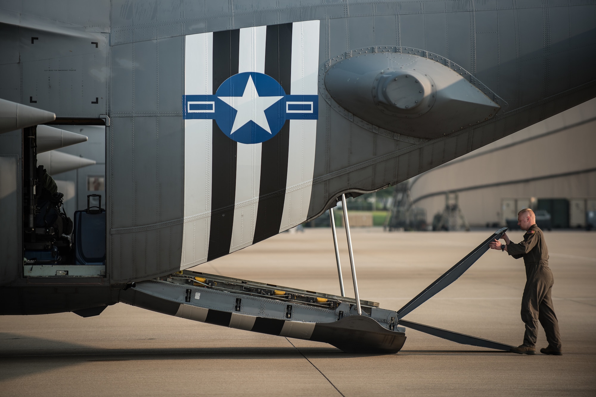 Senior Airman Brett Hook, a loadmaster for the 123rd Airlift Wing, closes the ramp on a C-130 Hercules aircraft at the Kentucky Air National Guard Base in Louisville, Ky., June 1, 2019, in preparation for a deployment to France. Hook and 30 other Kentucky Air Guardsmen will participate in the 75th-anniversary reenactment of D-Day there by airdropping U.S. Army paratroopers over Normandy on June 9. The aircraft has been striped with historically accurate Allied Forces livery in honor of the event, which turned the tide of World War II in the European theater. (U.S. Air National Guard photo by Dale Greer)