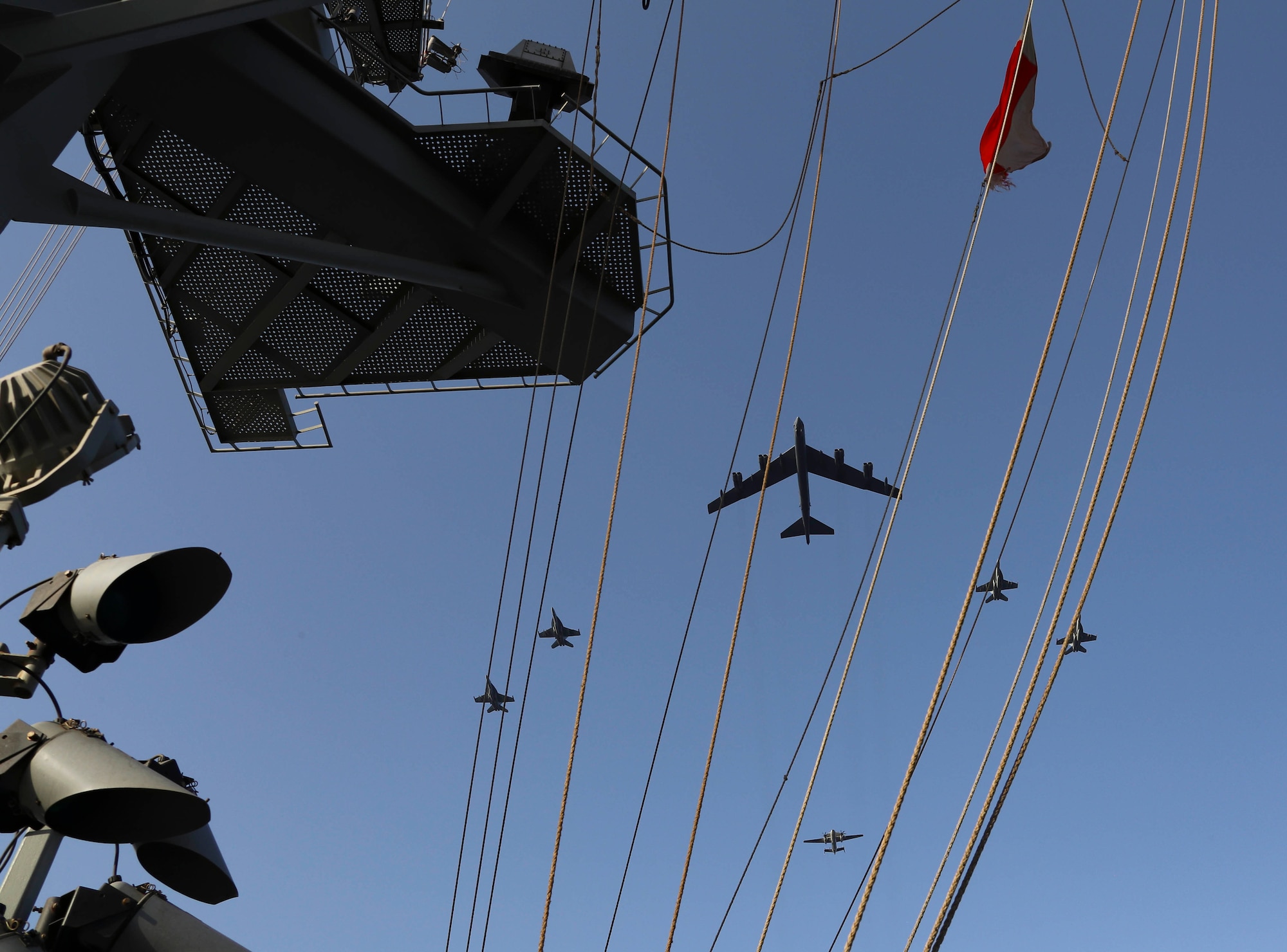 A photo of a B-52 and Abraham Lincoln Carrier Strike Group flying above the carrier.